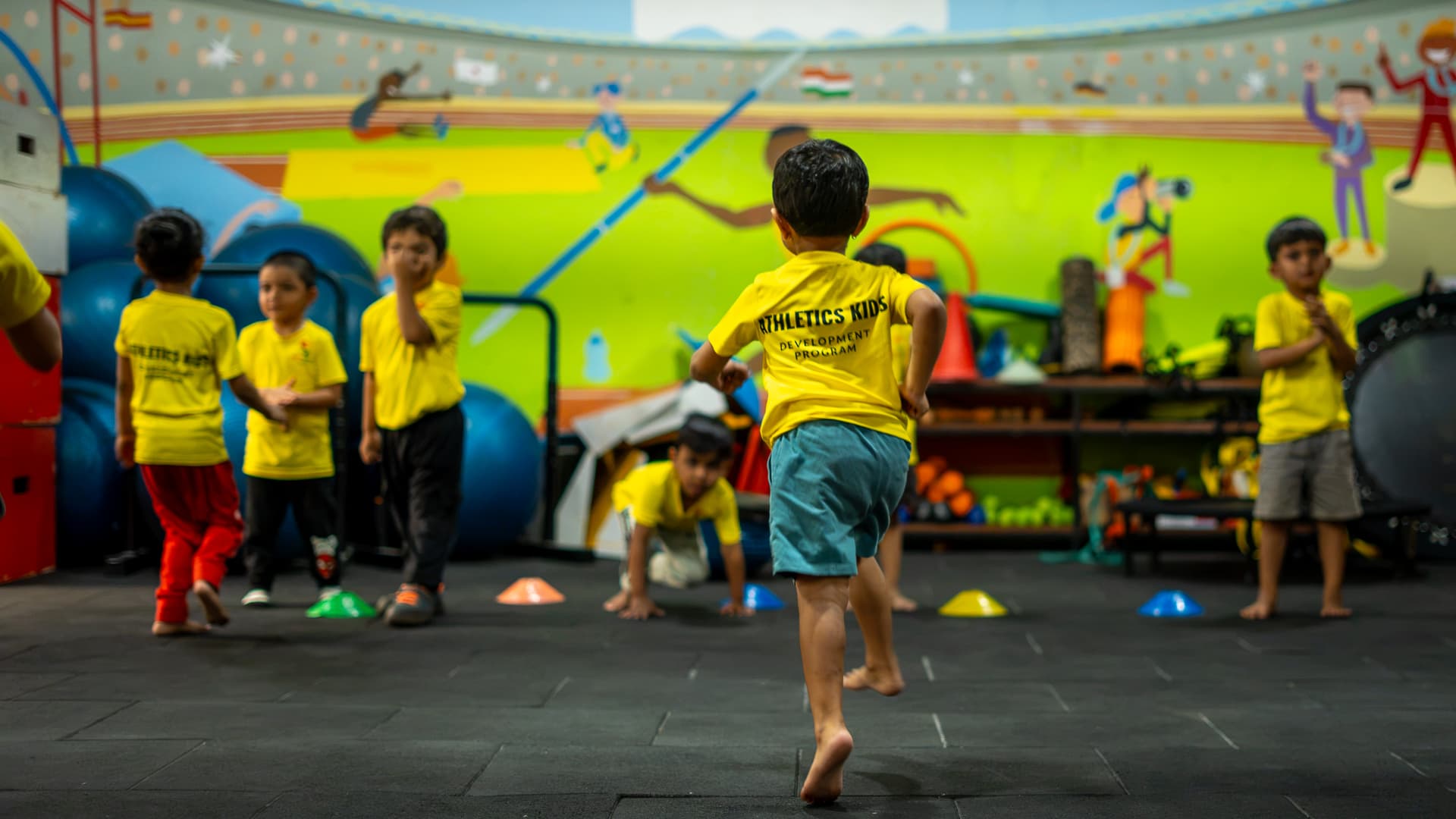 Children sprinting through a cone drill across the indoor athletic floor