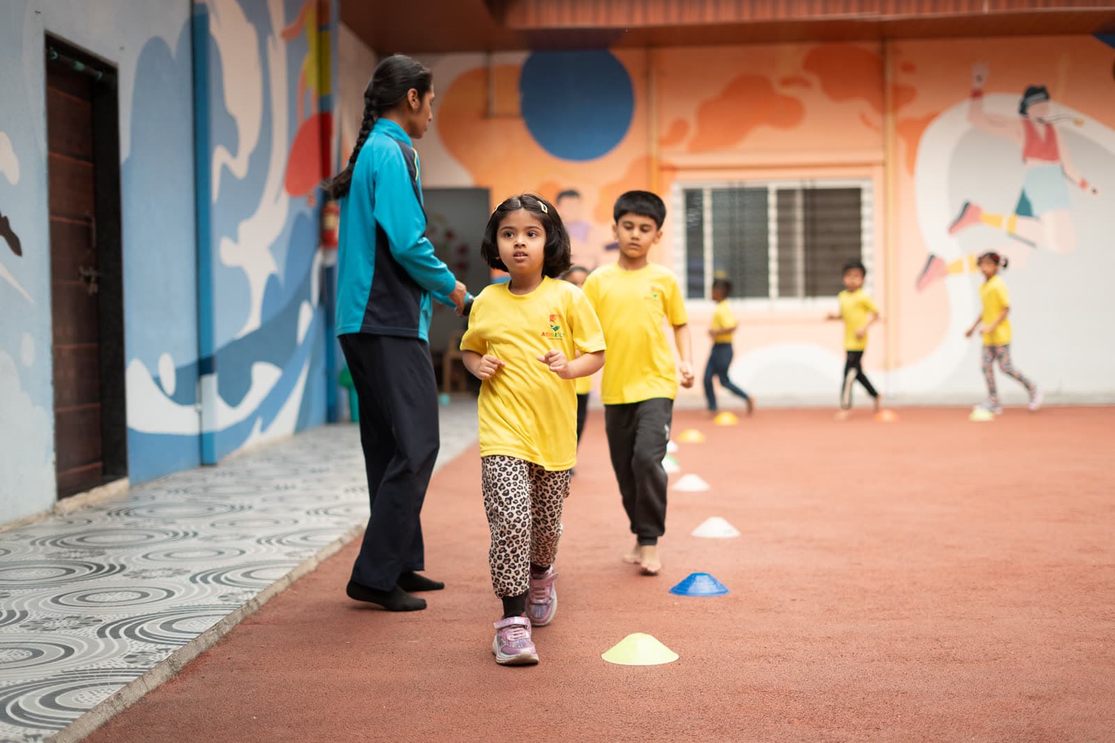 Children running a cone drill on the outdoor track at Athletots, Pashan