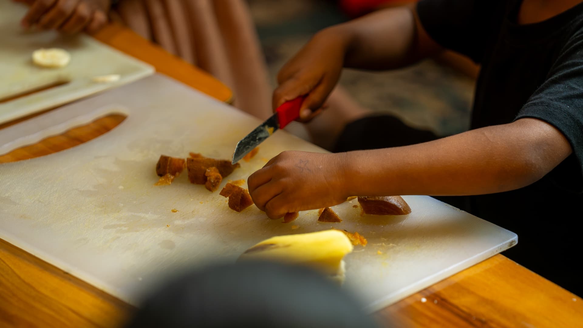 A child slicing fruit in the nutrition lab, learning a concept by doing it first