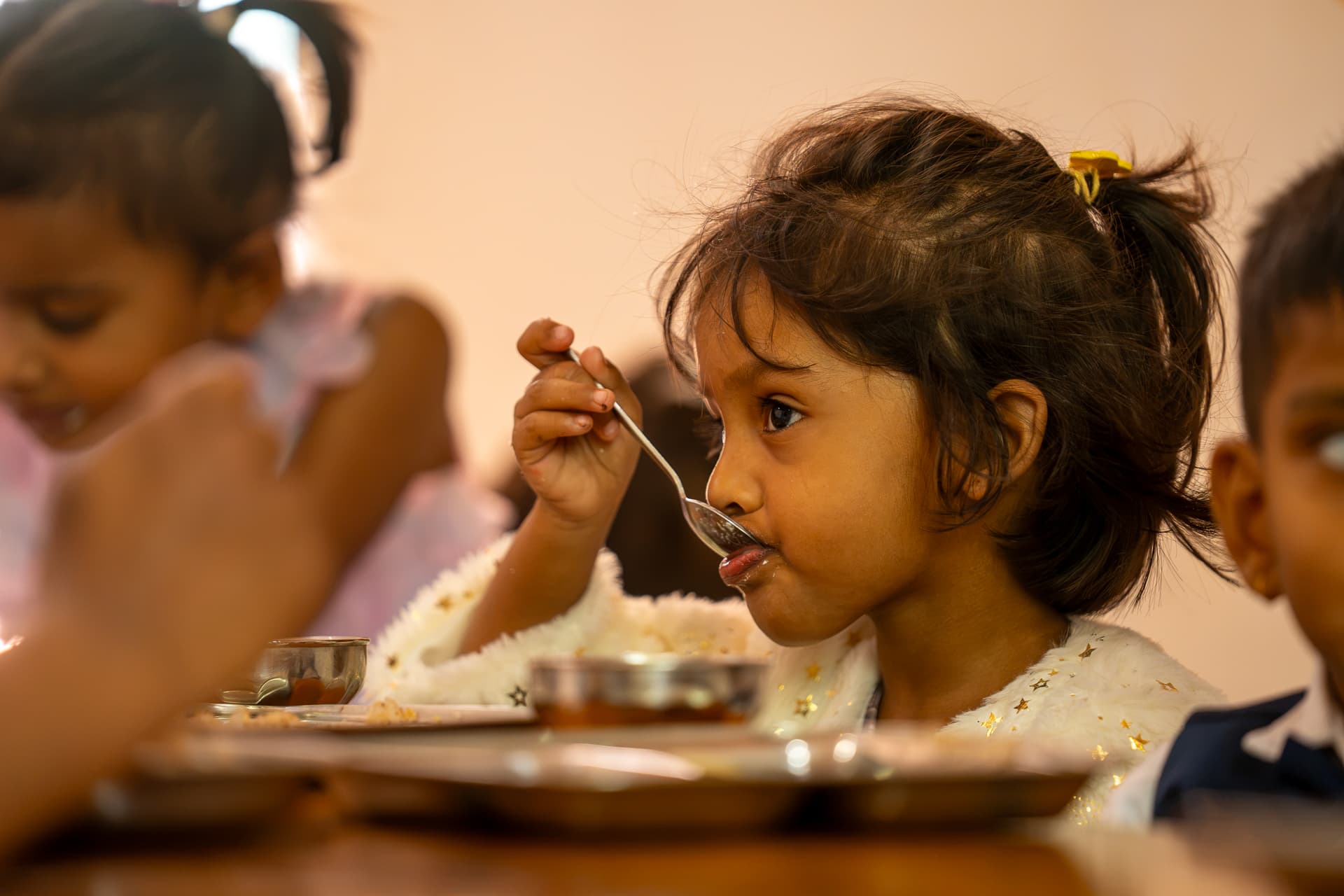 A Pioneers child eating lunch on her own at the campus dining table