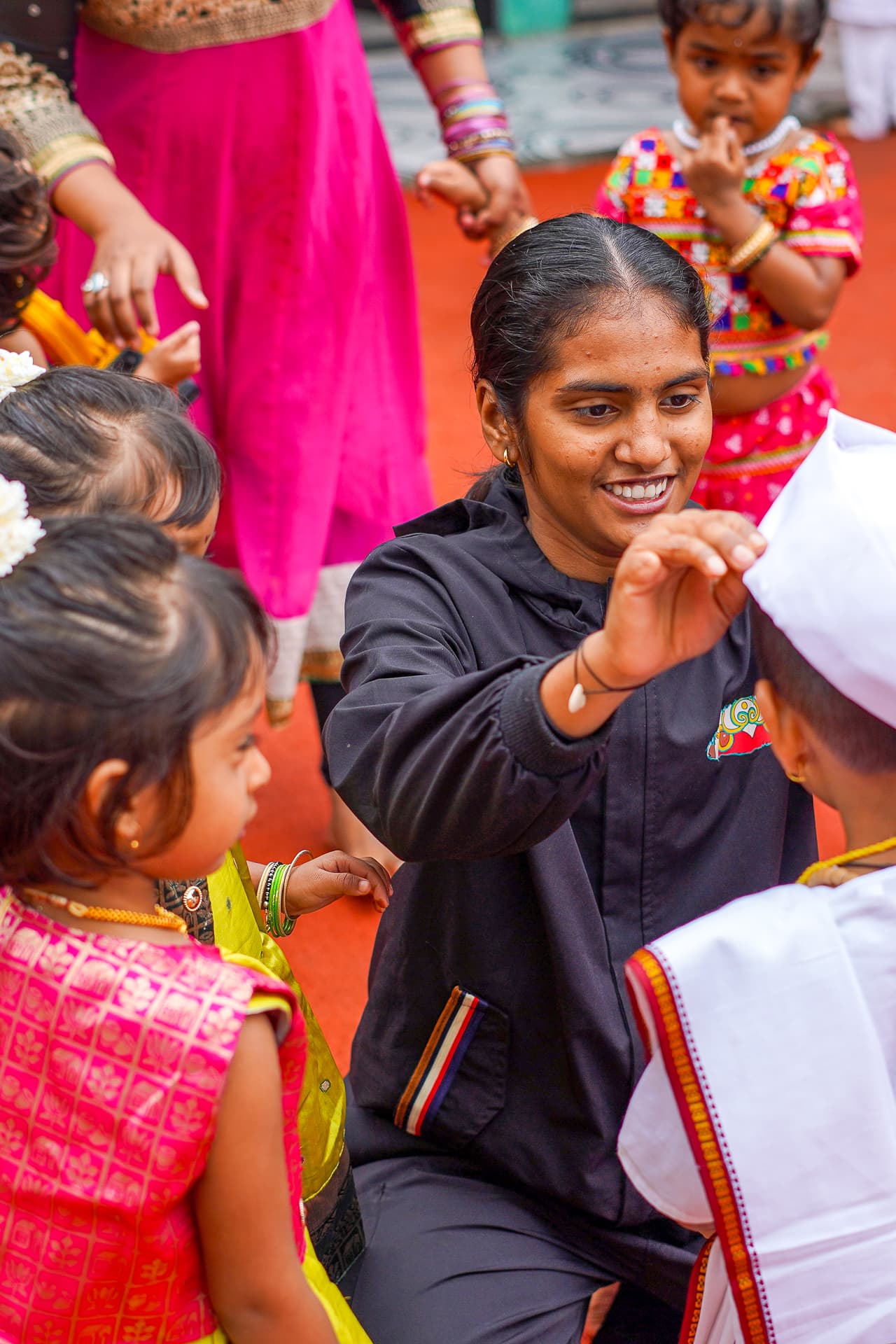 An Athletots mentor greeting children dressed up for a campus festival