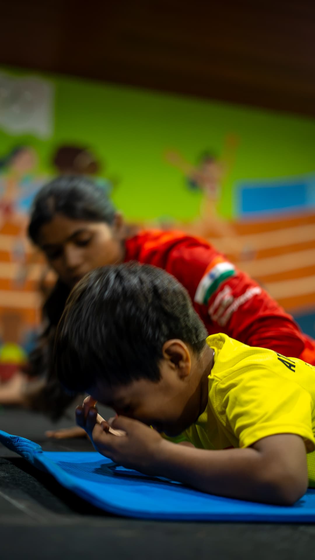 An Athletots mentor lying alongside a child on the mat, staying at eye level with him