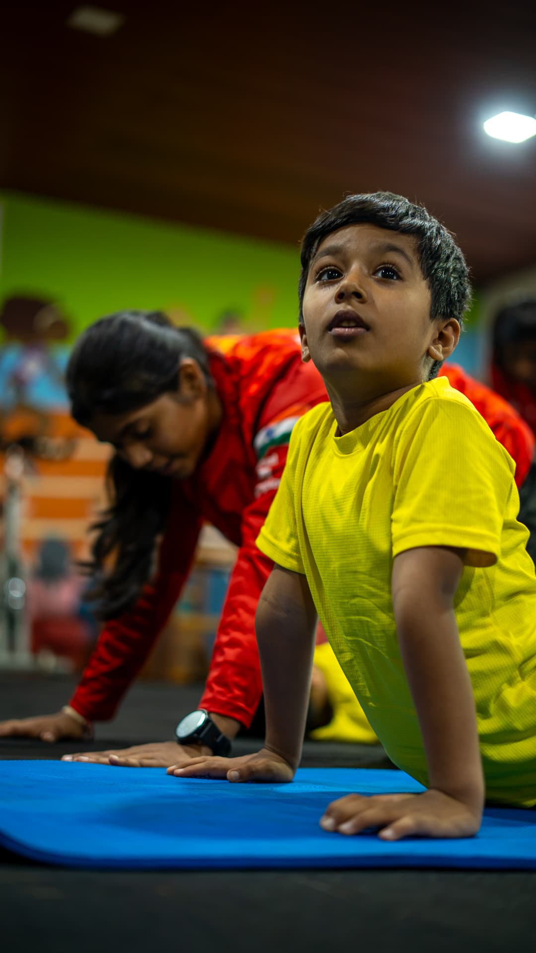 A mentor and child holding a cobra pose side by side during a yoga session