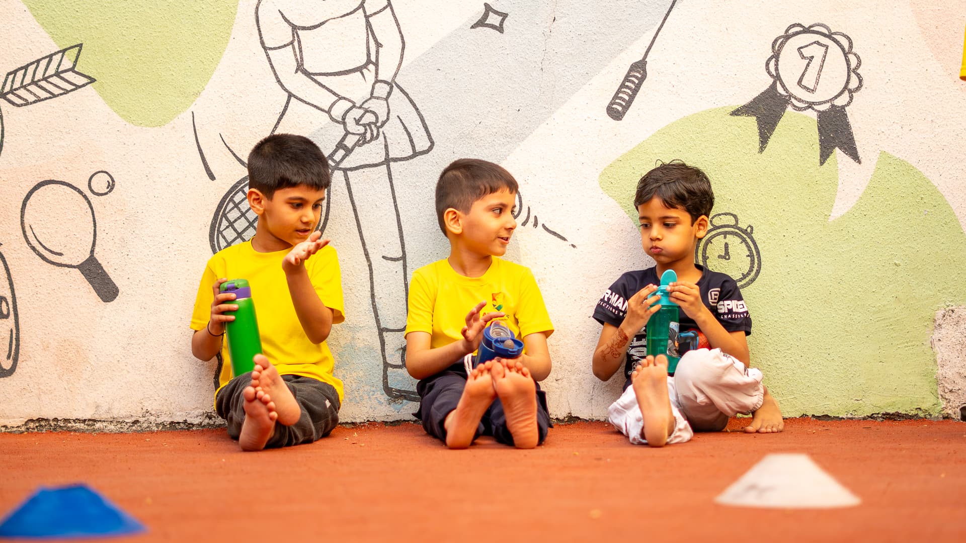 Three Athletots children sitting together with their water bottles during a break